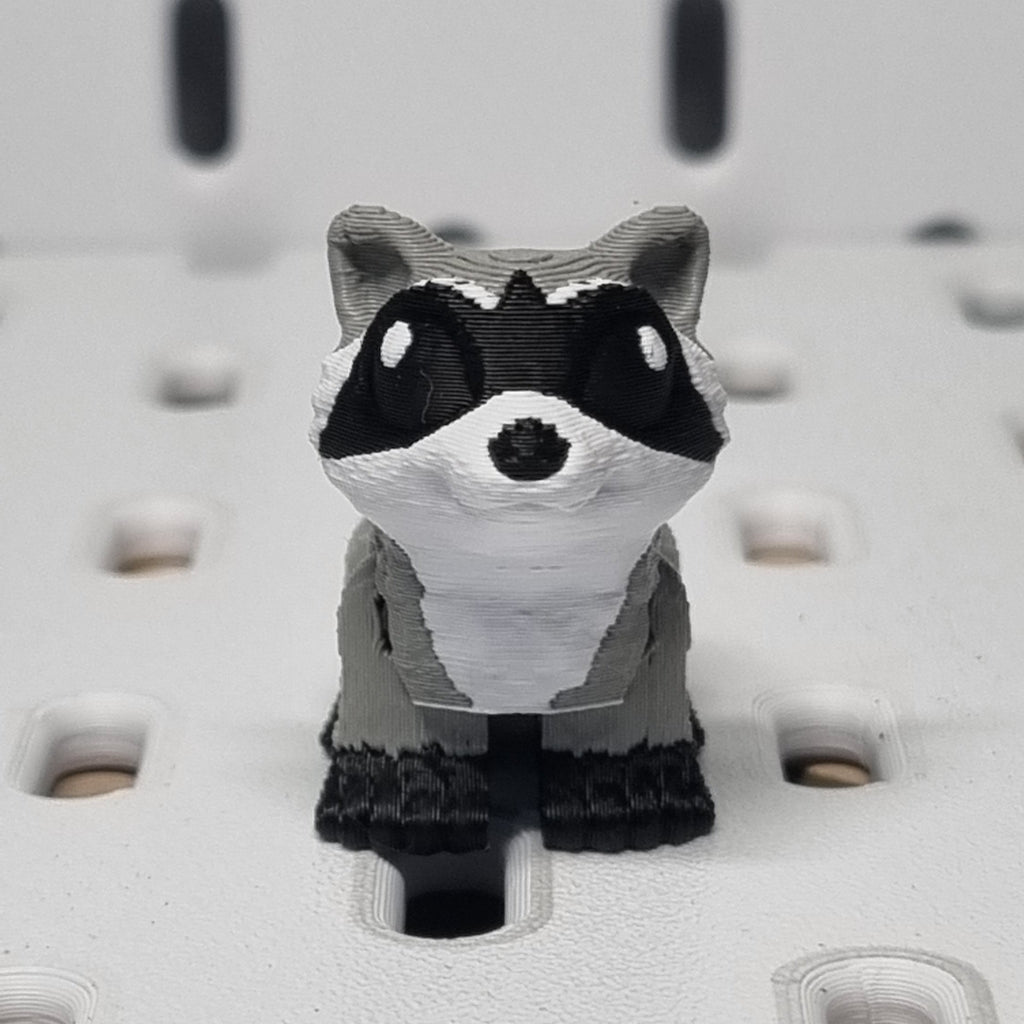 Small raccoon figurine on a textured white surface