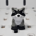 Small raccoon figurine on a textured white surface