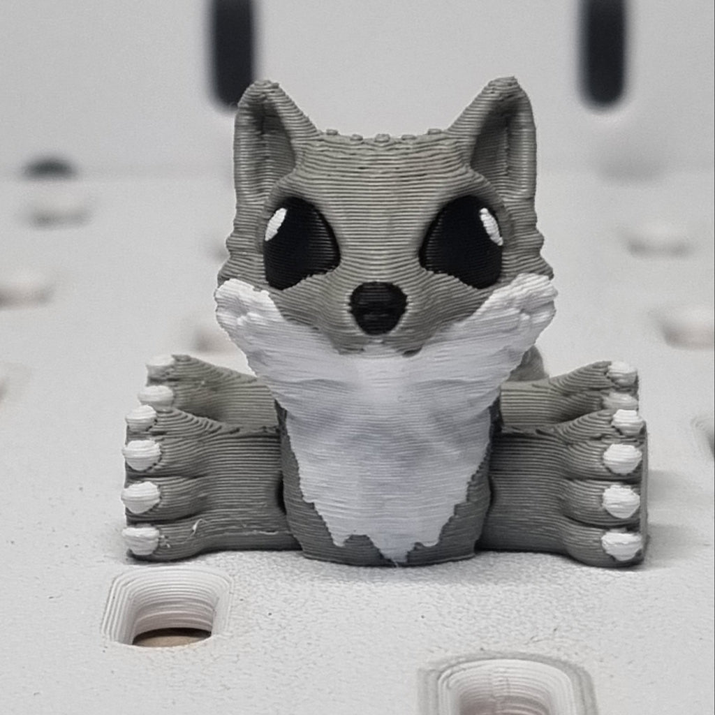 Gray bear-shaped object peeking out from a textured white surface